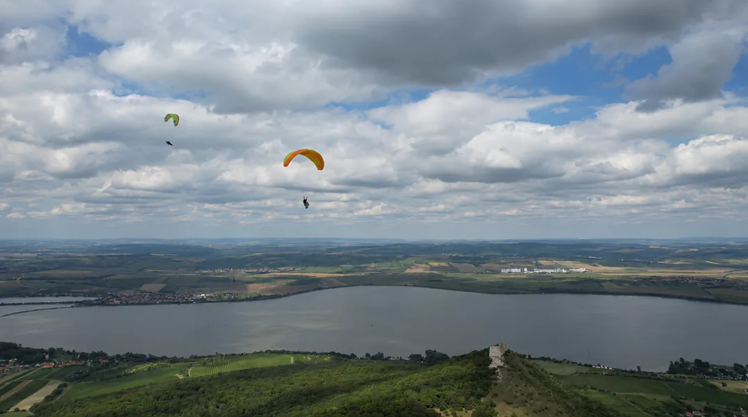 Two paragliders flying together over a lake and reservoir in Portugal