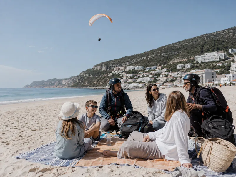 Family on the beach with a paraglider overhead