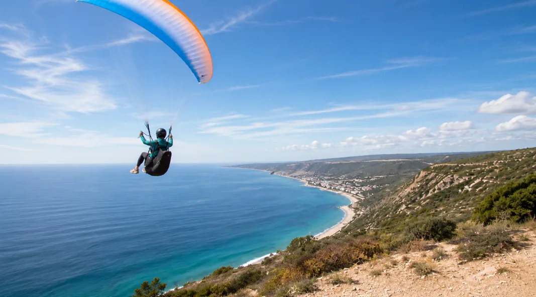 Paraglider in flight above the Sesimbra coast