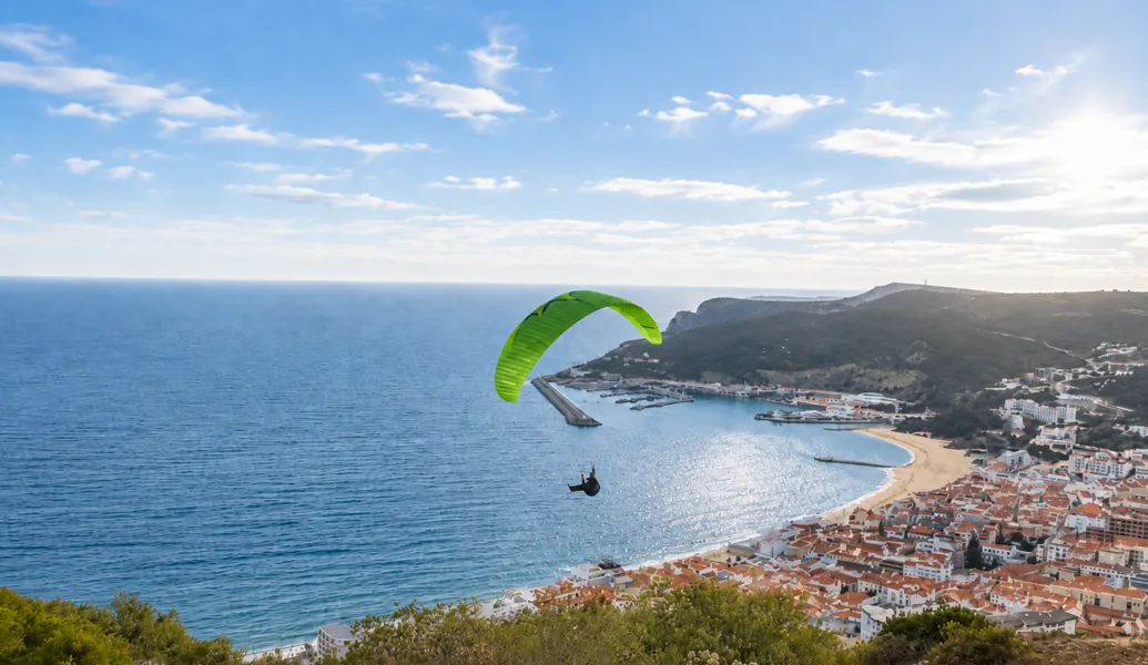 A paraglider soaring above Sesimbra bay