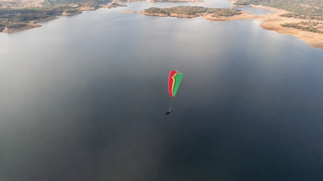 Paraglider above a calm lake during SIV training