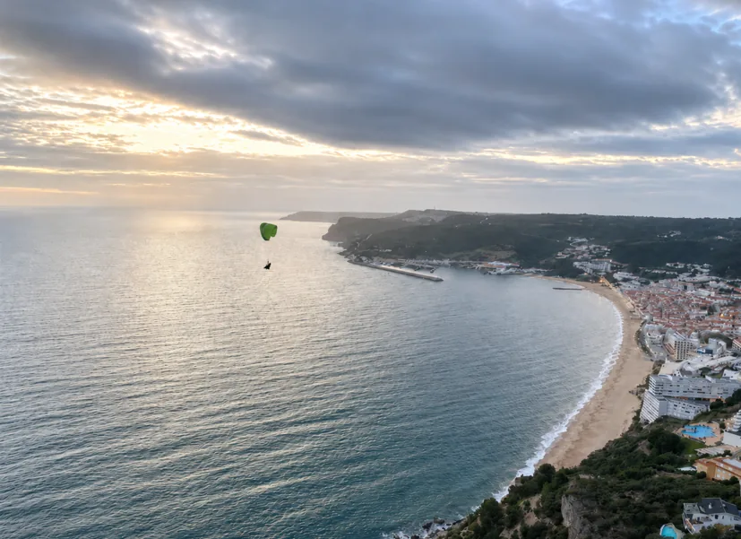 Paraglider at golden sunset above Sesimbra