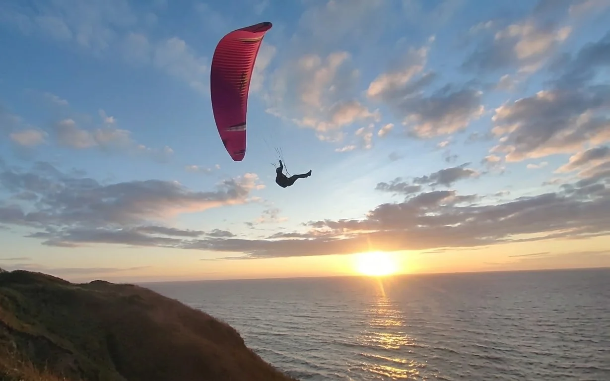 Parakite pilot on a small, fast wing above the Atlantic at sunset near Sesimbra, Portugal