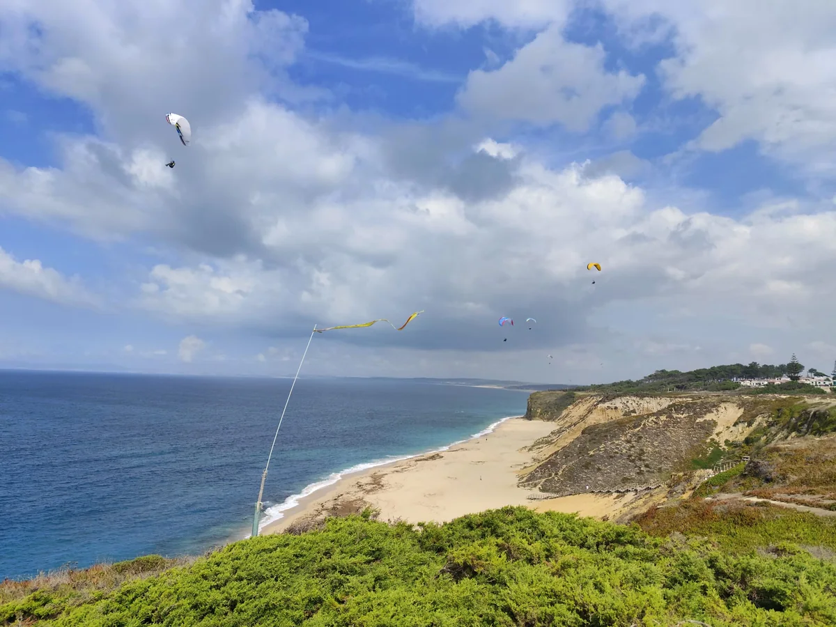 Paragliders soaring above the beach and cliffs at Praia das Bicas, Portugal