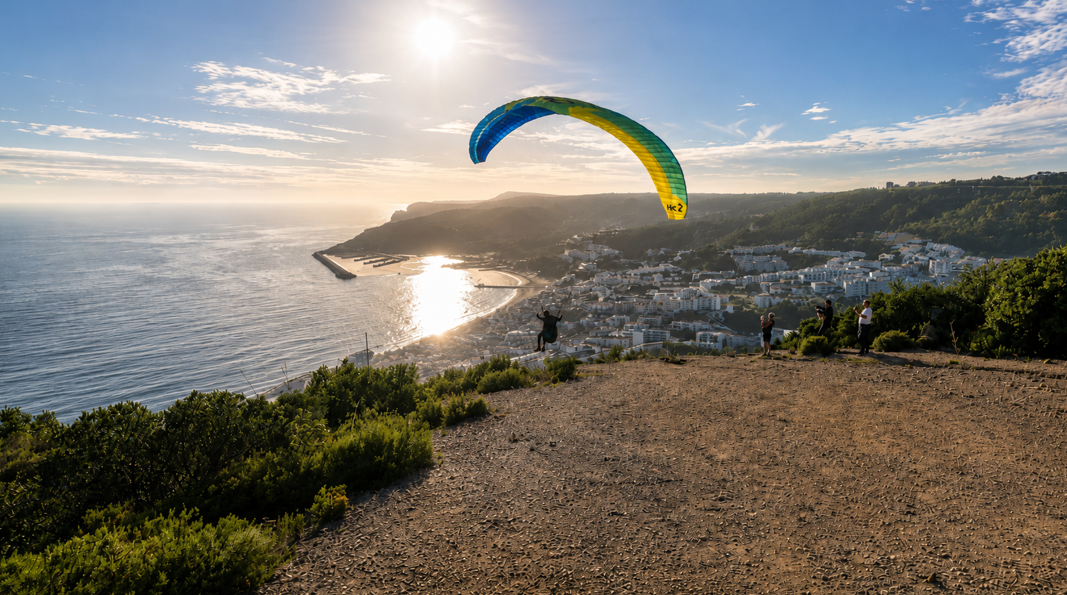Paraglider soaring above Sesimbra town and bay at golden hour, Portugal